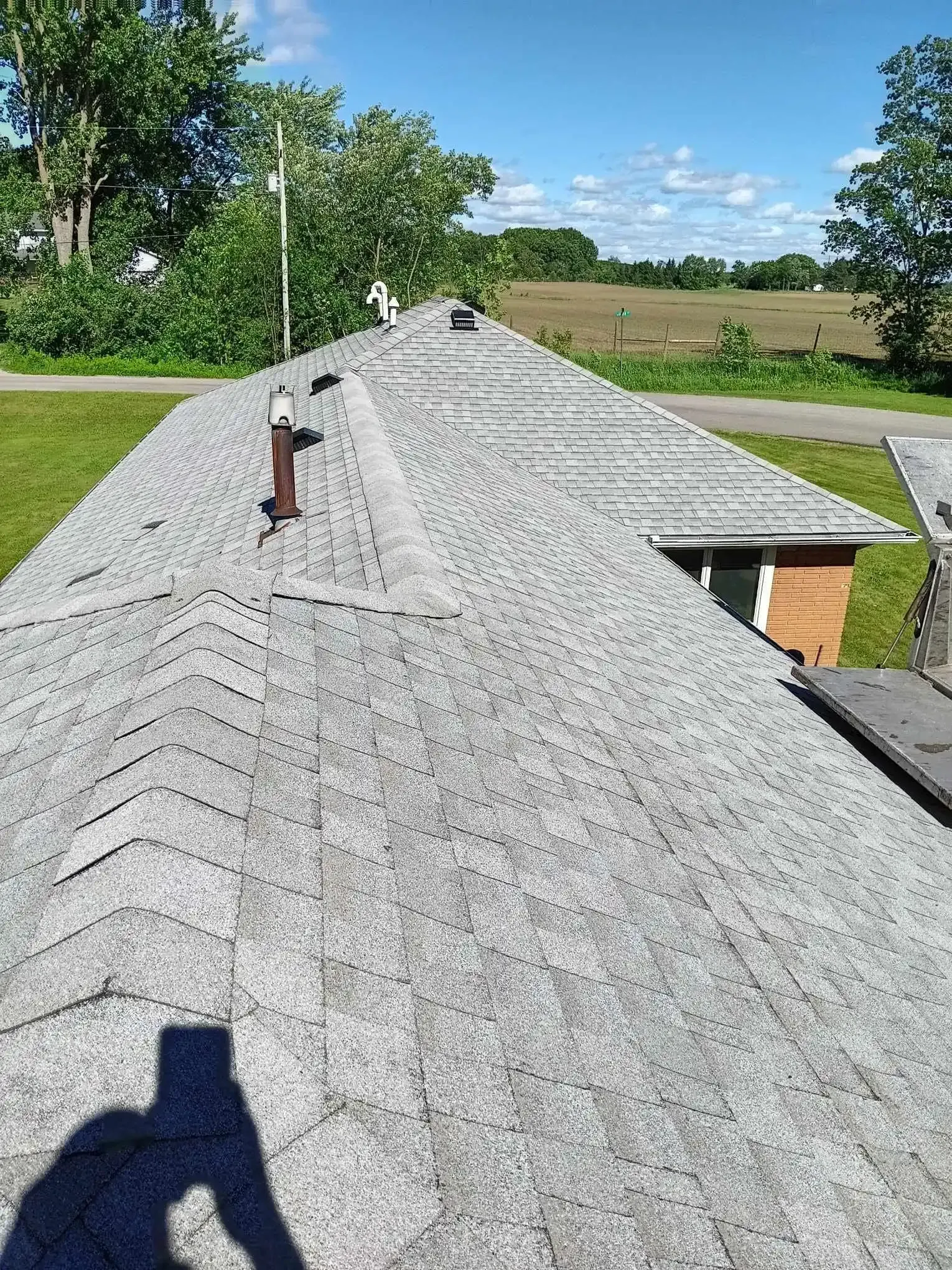 Completed asphalt shingle roof with attic ventilation vents on a Grant, MI home